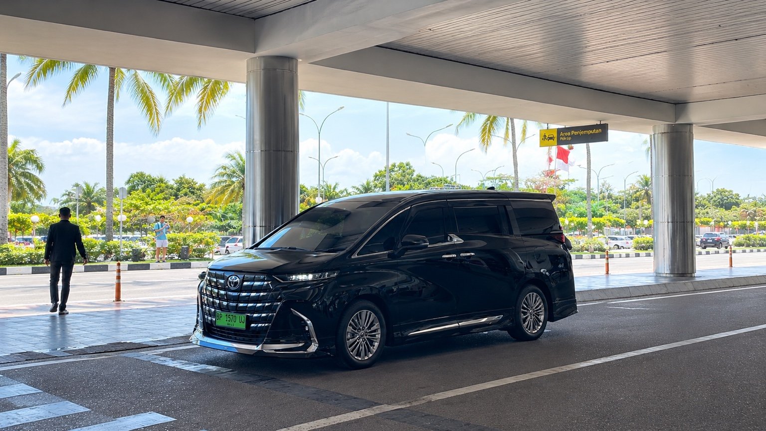 Toyota Alphard hitam di area penjemputan beratap di Batam.