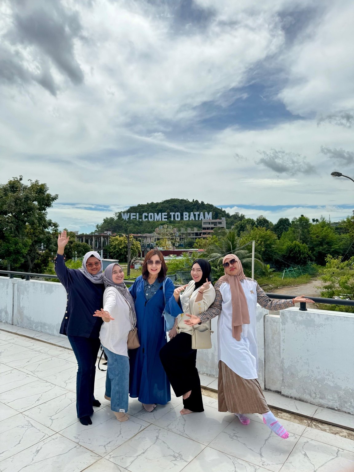 Five travellers with the Welcome to Batam sign in the background